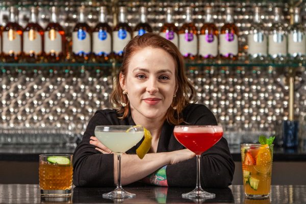 Sarah posing with a variety of current spirits cocktails.
